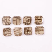 Emerald step cut lab grown diamonds with champagne tone and visible natural-style inclusions arranged in two rows on a white background.