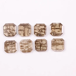 Emerald step cut lab grown diamonds with champagne tone and visible natural-style inclusions arranged in two rows on a white background.