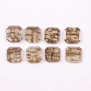 Emerald step cut lab grown diamonds with champagne tone and visible natural-style inclusions arranged in two rows on a white background.