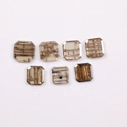 Emerald cut lab grown diamond featuring natural-inspired linear inclusions in a step cut octagonal shape, showcasing warm champagne tones and geometric internal patterns on a clean white background.