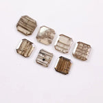 Emerald cut lab grown diamond featuring natural-inspired linear inclusions in a step cut octagonal shape, showcasing warm champagne tones and geometric internal patterns on a clean white background.
