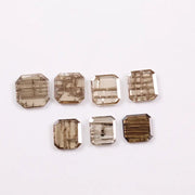 Emerald cut lab grown diamond featuring natural-inspired linear inclusions in a step cut octagonal shape, showcasing warm champagne tones and geometric internal patterns on a clean white background.