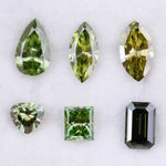 Six fancy color lab grown diamonds in green and yellow shades displayed on white background, featuring pear, marquise, heart, princess, and emerald cuts.