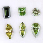 Six fancy color lab grown diamonds in green and yellow shades displayed on white background, featuring pear, marquise, heart, princess, and emerald cuts.