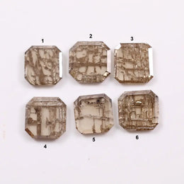 Six emerald cut octagonal lab grown diamonds featuring distinctive golden vein-like inclusions in a transparent champagne-toned base, displayed on a white background.