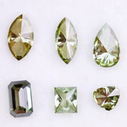 Six fancy color lab grown diamonds in green and yellow shades displayed on white background, featuring pear, marquise, heart, princess, and emerald cuts.