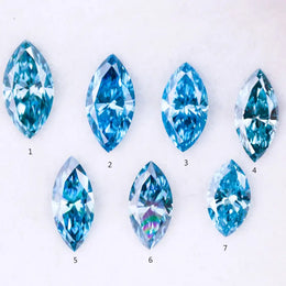 Seven marquise cut blue lab grown diamonds in vivid teal and aqua shades displayed on a white background, showcasing brilliant faceting and elongated shapes for engagement rings or custom jewelry.