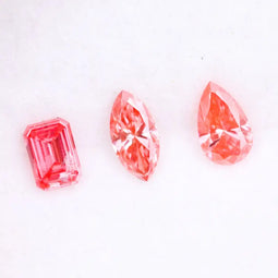 Three lab grown pink diamonds displayed on a white background, including a pear cut, marquise cut, and emerald cut fancy vivid pink loose diamonds for custom fine jewelry and engagement rings.