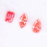 Three lab grown pink diamonds displayed on a white background, including a pear cut, marquise cut, and emerald cut fancy vivid pink loose diamonds for custom fine jewelry and engagement rings.