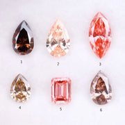 Six fancy colored lab grown diamonds including pear, marquise, and emerald cuts in pink, peach, champagne, and brown tones displayed on a white background, ideal for custom engagement rings and fine jewelry.