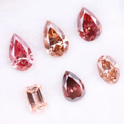Six lab grown fancy colored diamonds in pink, blush, champagne and deep rose tones featuring pear, oval and emerald cuts displayed on a white background for fine jewelry design.