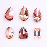 Six lab grown fancy colored diamonds in pink, blush, champagne and deep rose tones featuring pear, oval and emerald cuts displayed on a white background for fine jewelry design.