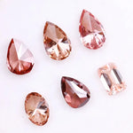 Six lab grown fancy colored diamonds in pink, blush, champagne and deep rose tones featuring pear, oval and emerald cuts displayed on a white background for fine jewelry design.