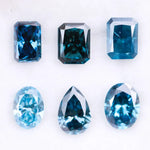 Six lab grown blue diamonds in emerald, oval and pear cuts displaying fancy deep ocean blue color arranged on white background for custom engagement ring and fine jewelry making.