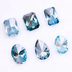 Six lab grown blue diamonds in emerald, oval and pear cuts displaying fancy deep ocean blue color arranged on white background for custom engagement ring and fine jewelry making.