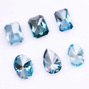 Six lab grown blue diamonds in emerald, oval and pear cuts displaying fancy deep ocean blue color arranged on white background for custom engagement ring and fine jewelry making.