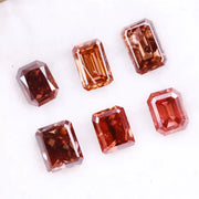 Six lab grown fancy orange pink emerald cut diamonds displayed on a white background, rectangular step cut loose grown diamonds in various reddish peach shades for engagement rings and fine jewelry.