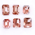 Six lab grown fancy orange pink emerald cut diamonds displayed on a white background, rectangular step cut loose grown diamonds in various reddish peach shades for engagement rings and fine jewelry.