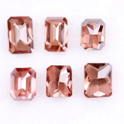 Six lab grown fancy orange pink emerald cut diamonds displayed on a white background, rectangular step cut loose grown diamonds in various reddish peach shades for engagement rings and fine jewelry.