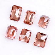 Six lab grown fancy orange pink emerald cut diamonds displayed on a white background, rectangular step cut loose grown diamonds in various reddish peach shades for engagement rings and fine jewelry.