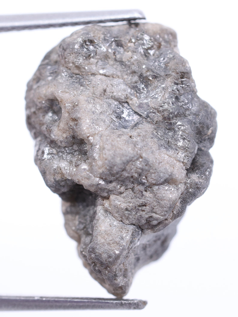 grey raw diamond held by tweezers on a white background