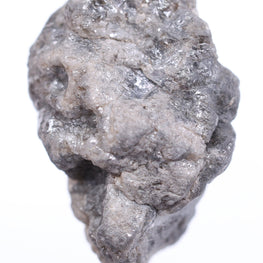 grey raw diamond held by tweezers on a white background
