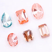 Lab grown fancy pink, peach, cognac and blue diamonds in oval, emerald and pear cuts displayed on white background, sustainable CVD created gemstones for fine jewelry.