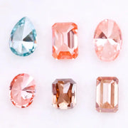 Lab grown fancy pink, peach, cognac and blue diamonds in oval, emerald and pear cuts displayed on white background, sustainable CVD created gemstones for fine jewelry.