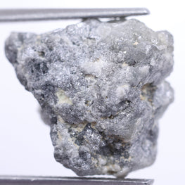 Raw diamond held by tweezers on a white background