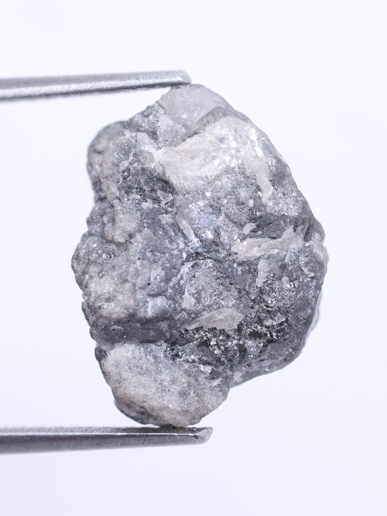 Raw diamond held by tweezers on a white background