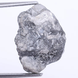 Raw diamond held by tweezers on a white background