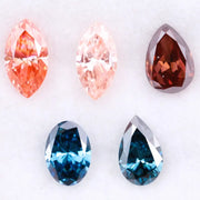 Collection of fancy color lab grown diamonds including pink marquise cut, light peach marquise, brown pear shape, blue oval cut and blue pear cut loose diamonds displayed on white background