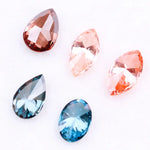 Collection of fancy color lab grown diamonds including pink marquise cut, light peach marquise, brown pear shape, blue oval cut and blue pear cut loose diamonds displayed on white background