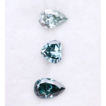 Three blue lab grown diamonds displayed on white background: pear cut light blue diamond (1), heart cut teal diamond (2), and deep blue pear shaped diamond (3), brilliant faceted loose stones for engagement ring or custom fine jewelry.