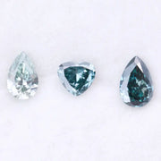 Three blue lab grown diamonds displayed on white background: pear cut light blue diamond (1), heart cut teal diamond (2), and deep blue pear shaped diamond (3), brilliant faceted loose stones for engagement ring or custom fine jewelry.