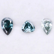 Three blue lab grown diamonds displayed on white background: pear cut light blue diamond (1), heart cut teal diamond (2), and deep blue pear shaped diamond (3), brilliant faceted loose stones for engagement ring or custom fine jewelry.