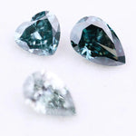 Three blue lab grown diamonds displayed on white background: pear cut light blue diamond (1), heart cut teal diamond (2), and deep blue pear shaped diamond (3), brilliant faceted loose stones for engagement ring or custom fine jewelry.