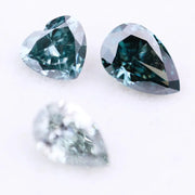 Three blue lab grown diamonds displayed on white background: pear cut light blue diamond (1), heart cut teal diamond (2), and deep blue pear shaped diamond (3), brilliant faceted loose stones for engagement ring or custom fine jewelry.
