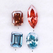 Four fancy color lab grown diamonds including oval and emerald cut blue stones and marquise and radiant cut red gemstones displayed on a white background.