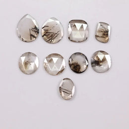 Assorted rose cut lab grown diamonds with natural-looking inclusions in oval, pear, round and cushion shapes arranged on white background for fine jewelry design.