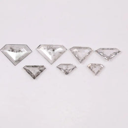 Seven clear lab grown diamonds in geometric faceted cuts arranged on white background, showing natural-style inclusions and transparent brilliance for jewelry making.