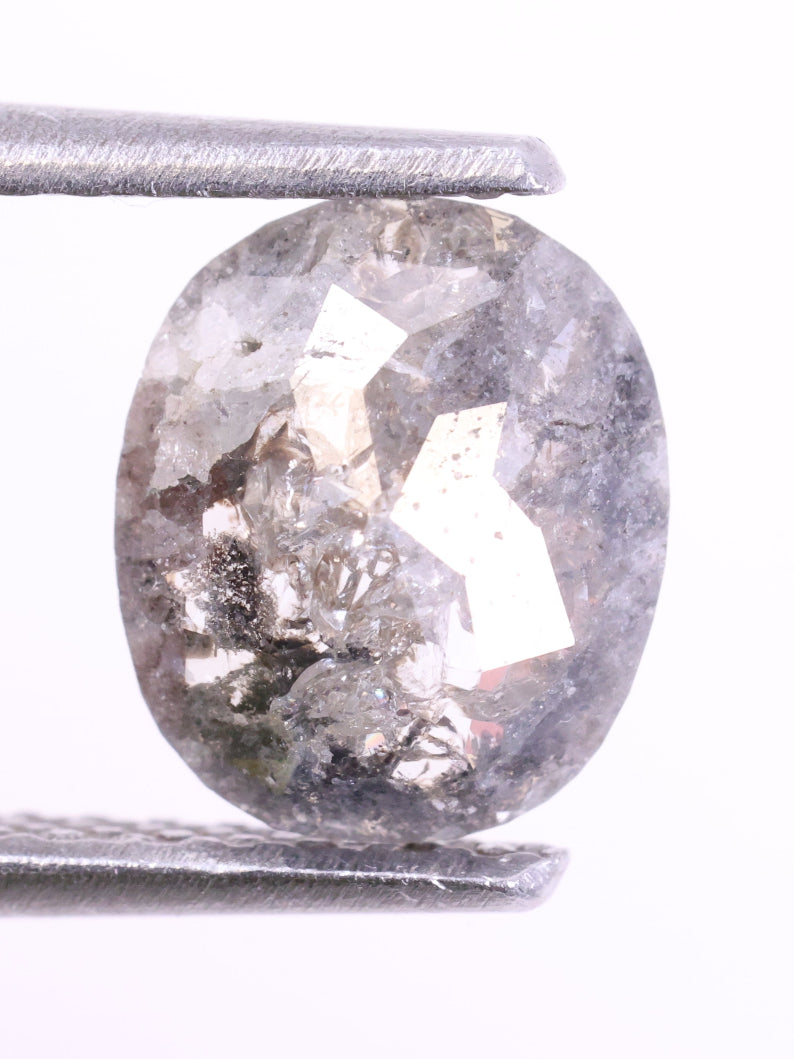 Oval-shaped diamond held between two silver prongs on a white background