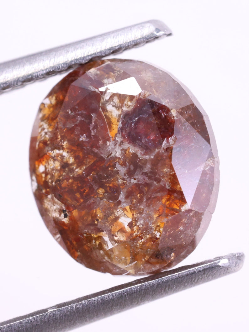 red color diamond held between tweezers on a white background