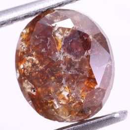 red color diamond held between tweezers on a white background