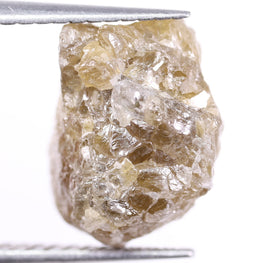 Raw diamond held by tweezers on a white background