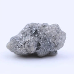Raw uncut diamond gemstone placed on neutral background showing natural clarity and texture