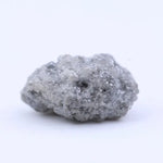 Raw uncut diamond gemstone placed on neutral background showing natural clarity and texture