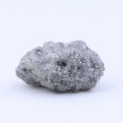 Raw uncut diamond gemstone placed on neutral background showing natural clarity and texture