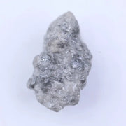 Raw uncut diamond gemstone placed on neutral background showing natural clarity and texture