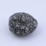 Close view of premium black diamond with bold dark sparkle and natural surface.